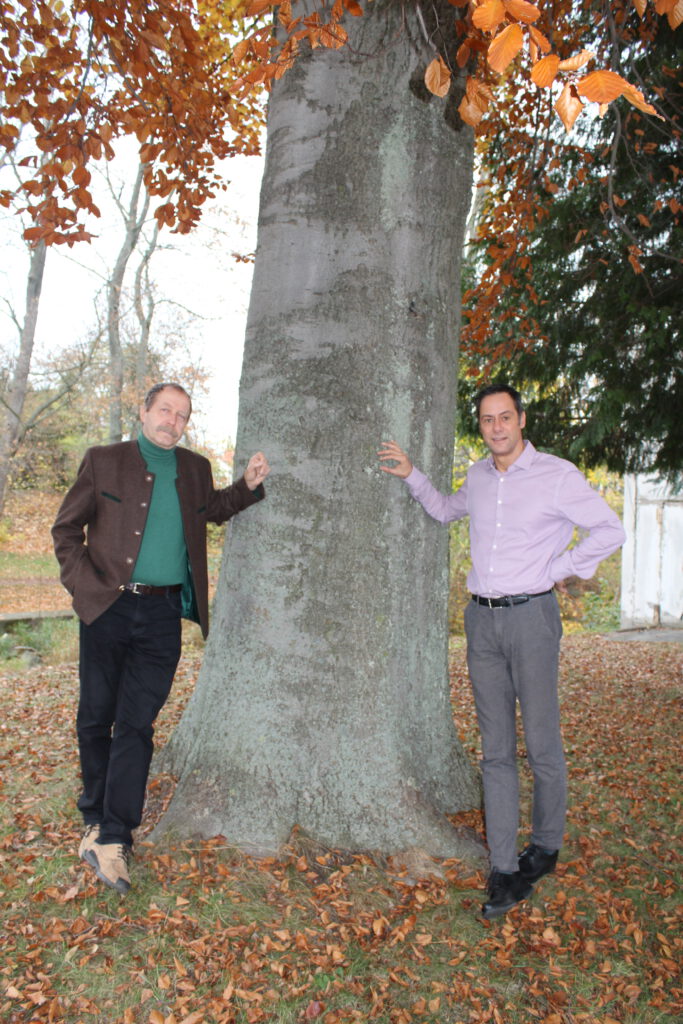 Der ehemalige Geschäftsführer Wolfgang Heyn (links) lehnt mit seinem Nachfolger Karsten Spinner (rechts) an einem Baum.